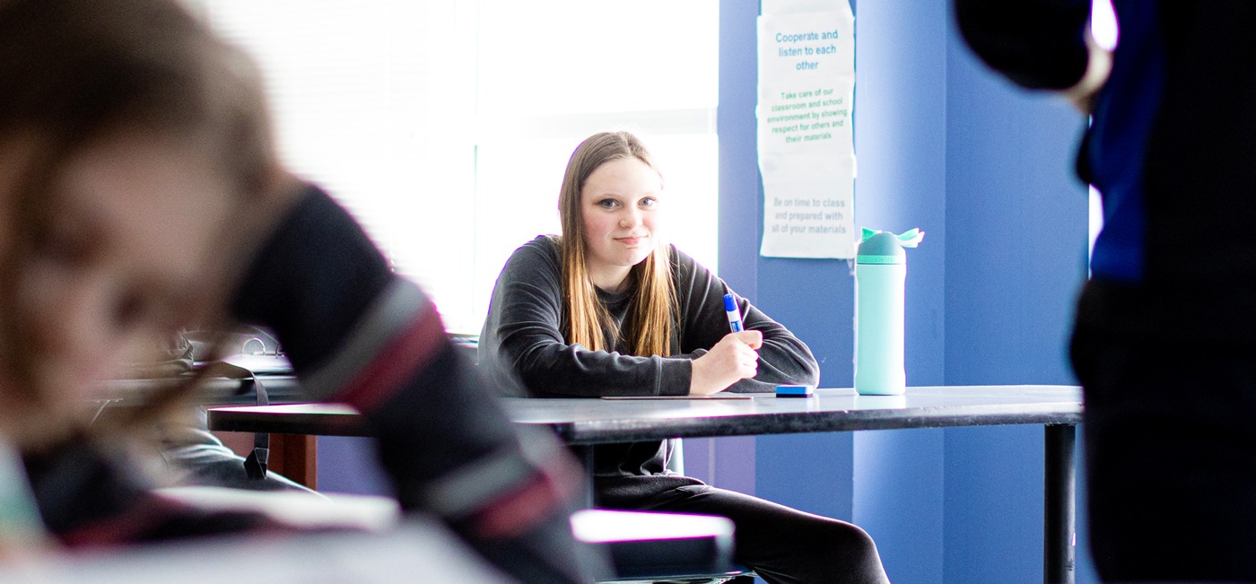 teenage girl sitting in classroom at desk