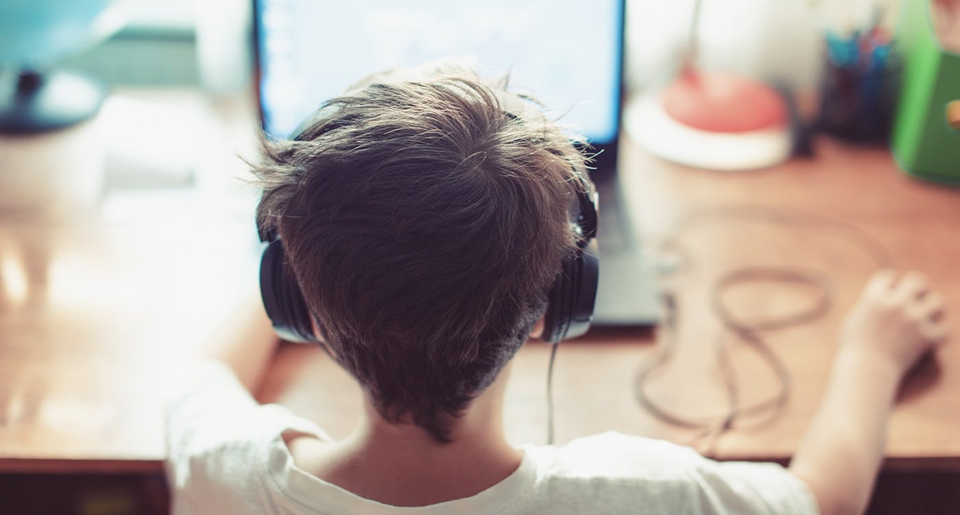 boy wearing headphones using assistive technology on a computer