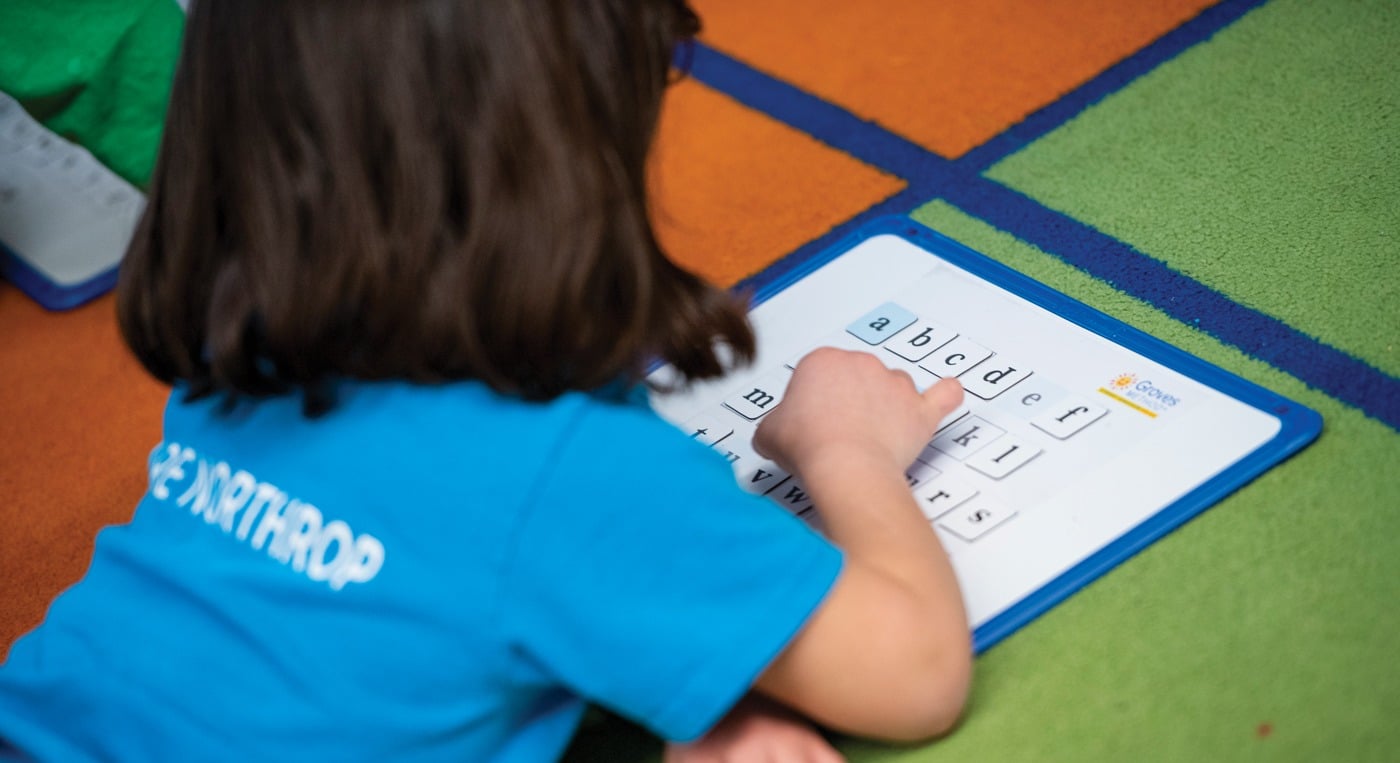 young girl student moving letters on a magnet board