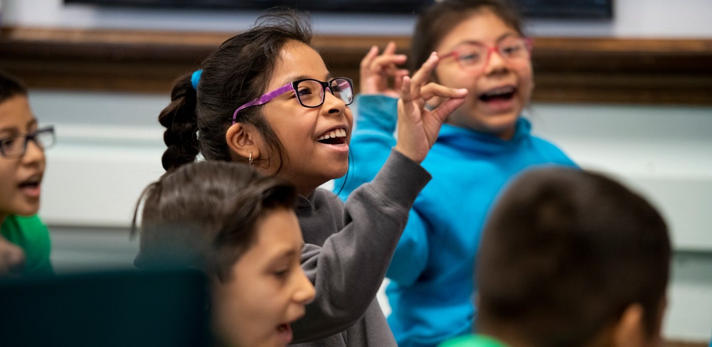 students smiling making phonics sounds with hand gestures