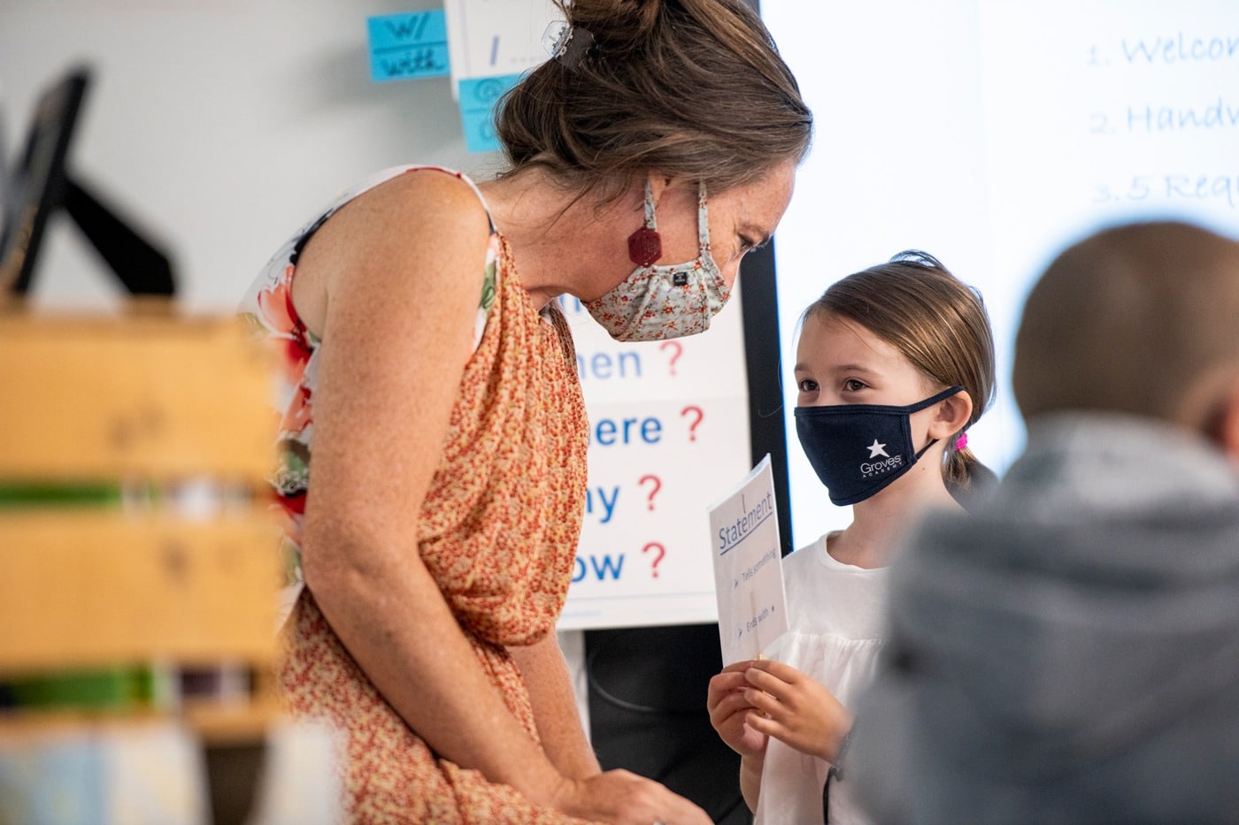 Teacherwearing mask talks to student